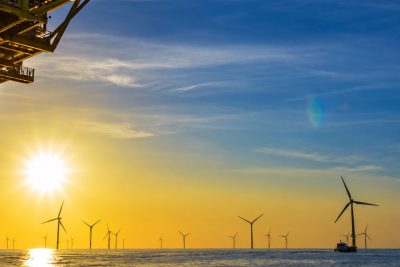 Offshore wind farm at sunrise seen from an offshore platform, with the N-ERGISE logo