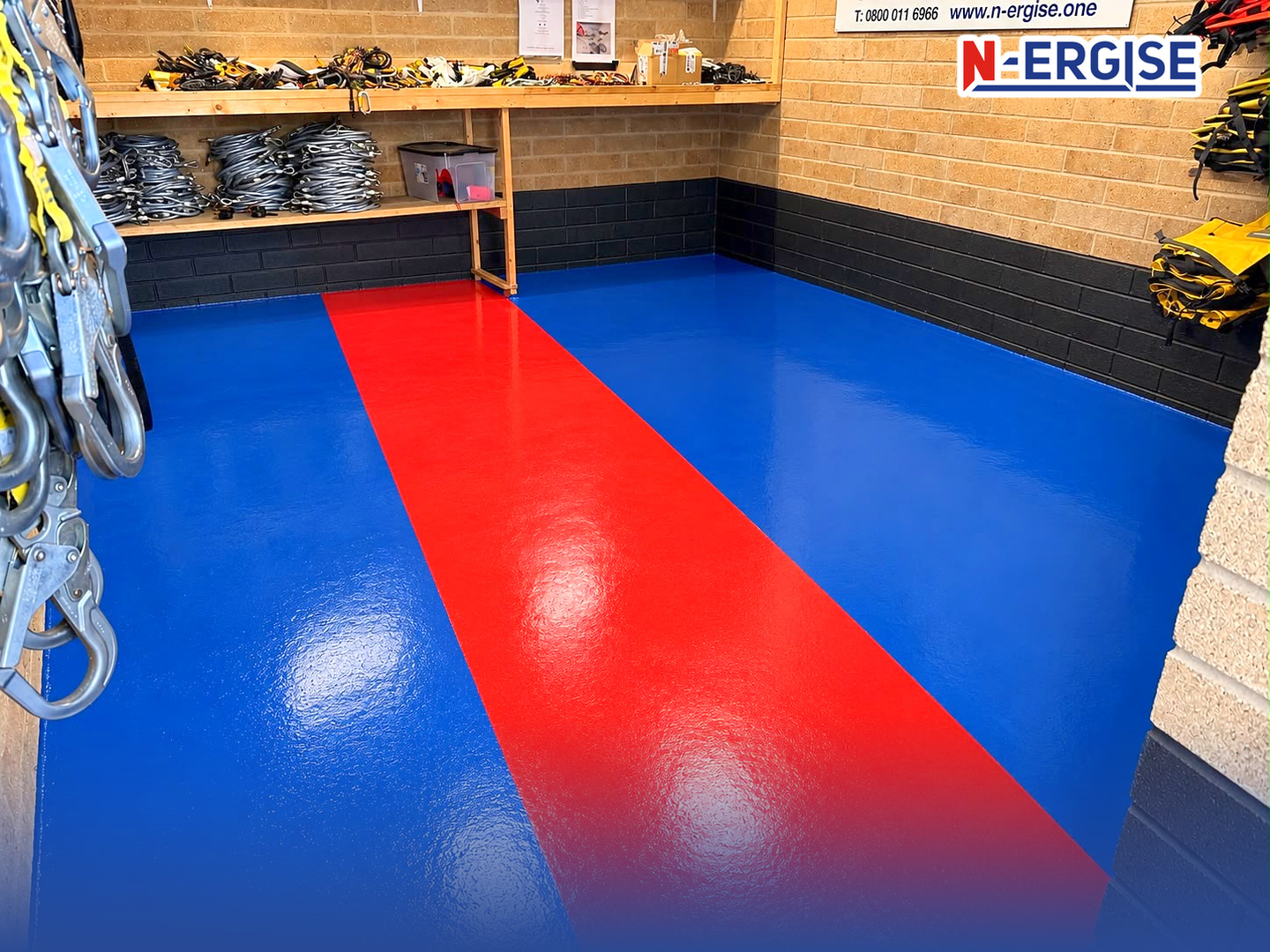 N-ERGISE kit room with a blue and red floor, shelves of coiled Rope Access lanyards, harnesses and kit bags on the wall